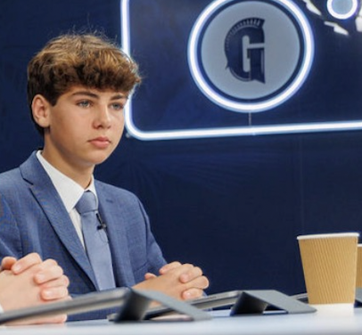 Ari speaking on a studio panel in a suit